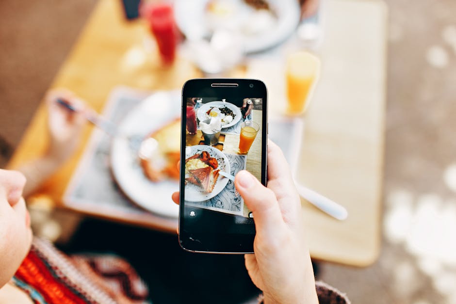 Overhead view of a person photographing a colorful brunch spread with a smartphone