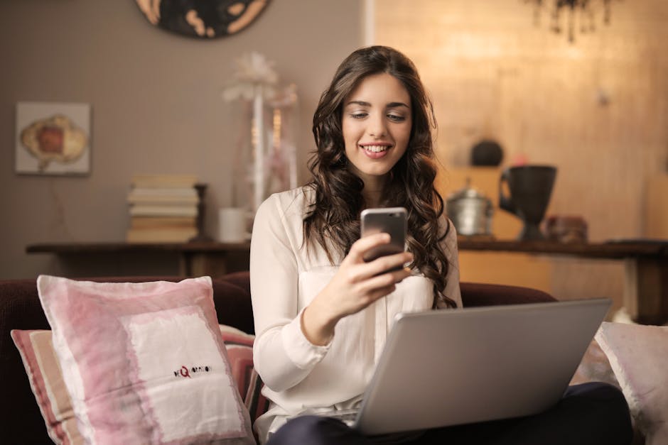 A woman enjoying leisure time using her smartphone and laptop in a cozy living room